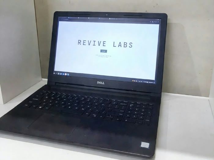 Dell Inspiron laptop on a white shelf, showing the Revive Labs website